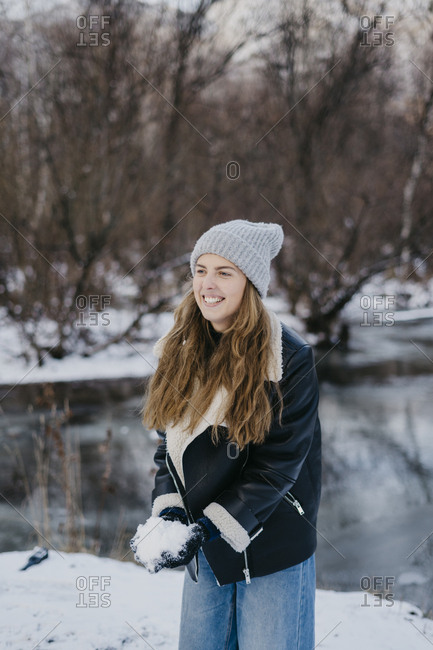 beautiful girl with a snowball in hand against the background of a winter river