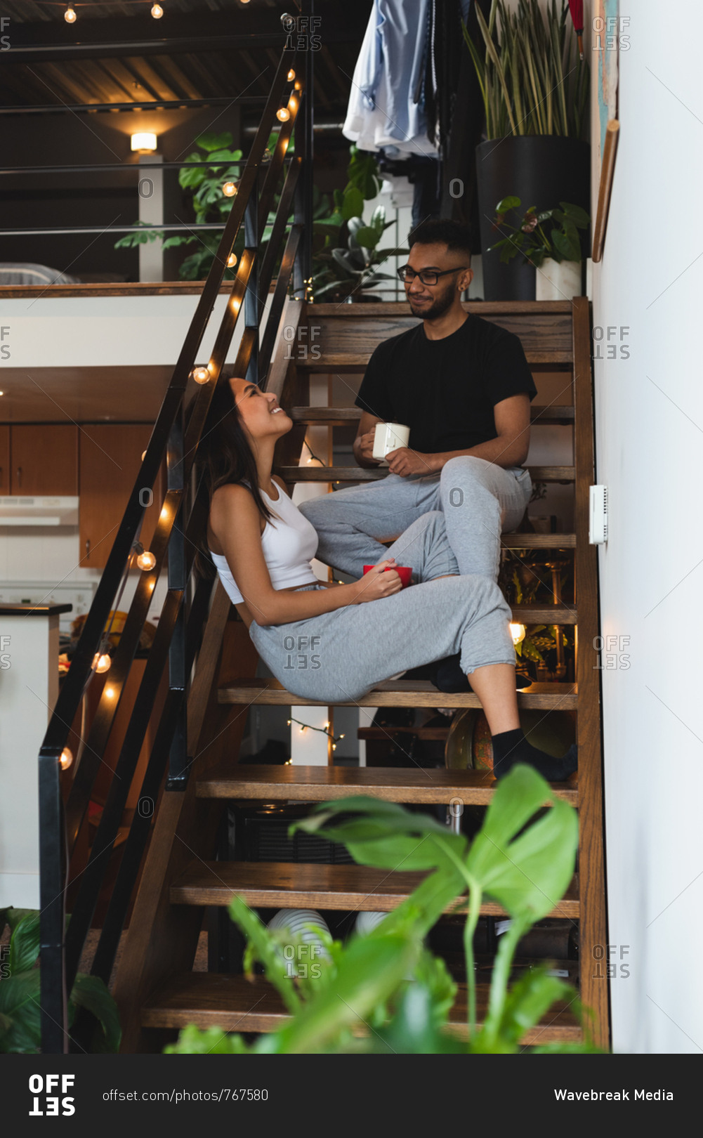 Couple interacting with each other while having coffee in stairs at home