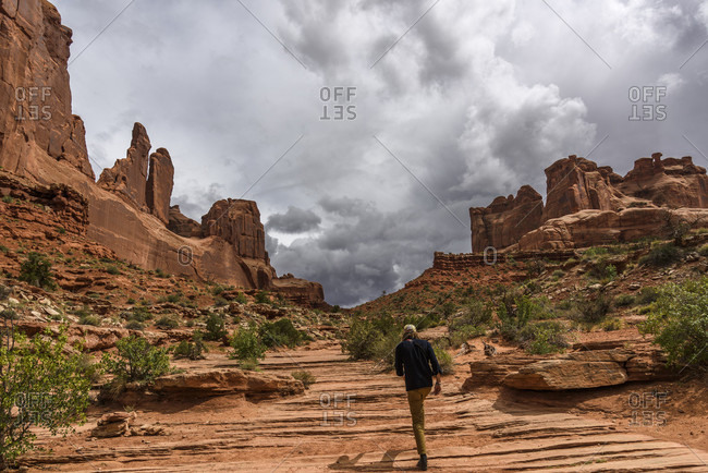 Rear view of man hiking in Park Avenue, Arches National Park, Utah, USA