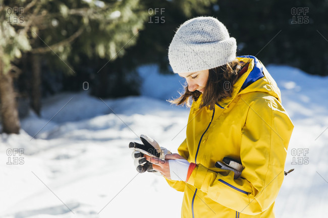 January 31, 2017: Side view shot of young woman using phone outdoors in winter, Whistler, British Columbia, Canada