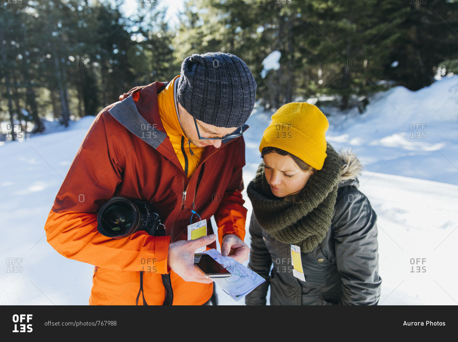 Waist up shot of man and woman checking map while hiking in winter, Whistler, British Columbia, Canada