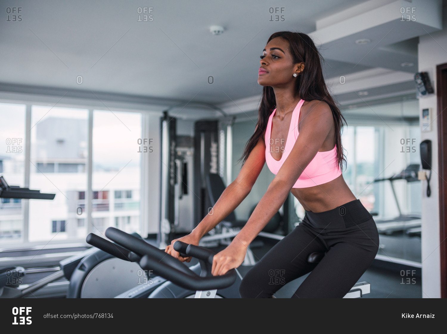Skinny African American woman doing cycling cardio in modern light gym, Panama city
