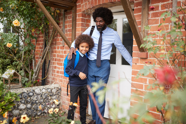 Pre-teen schoolboy wearing uniform with his father closing front door and leaving home in the morning, selective focus
