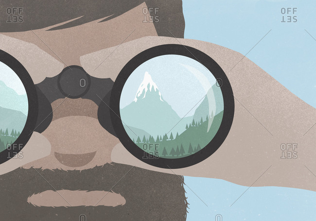 Reflection of a mountains in binoculars held by a man with a beard