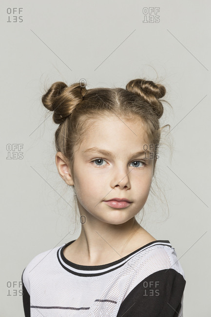 Portrait of young girl with double hair buns against grey background stock  photo - OFFSET