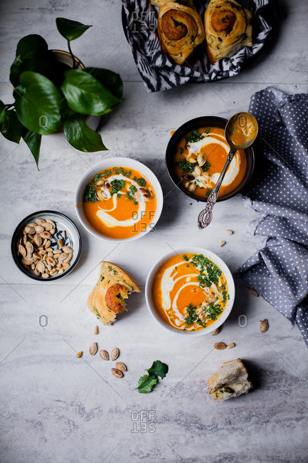 Bowls of homemade squash soup served with freshly baked rolls