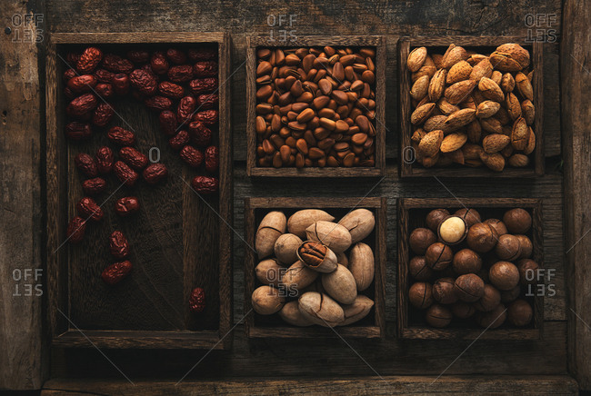 Variety of nuts in shells and dates sorted in wooden boxes