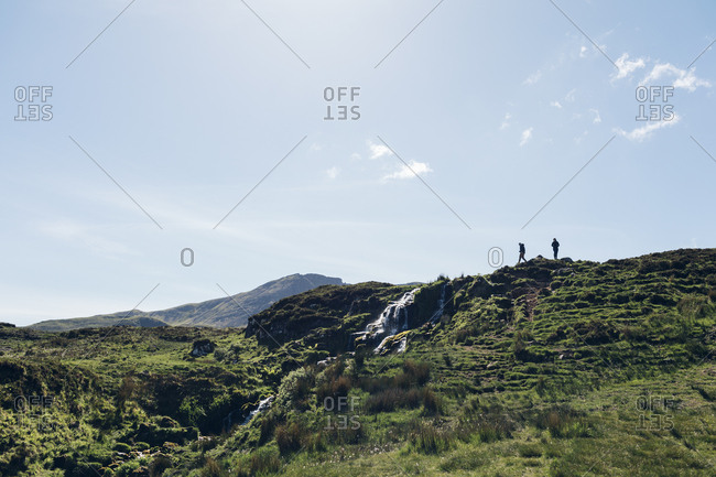 People hiking on hill on Isle of Skye, Scotland