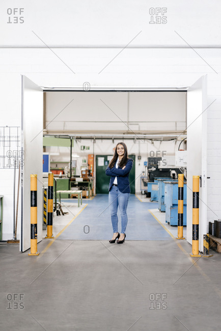 Confident woman working in high tech enterprise- standing in factory workshop with arms crossed