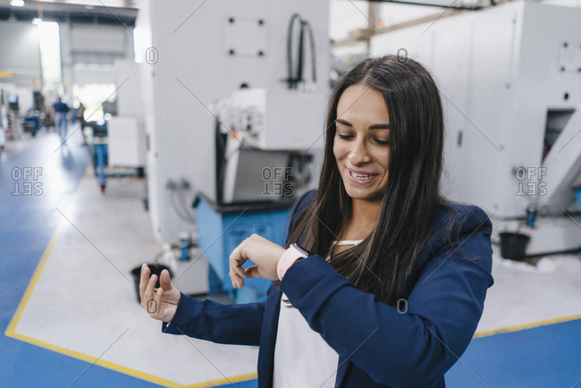 Confident woman working in high tech enterprise- using smartwatch for a call