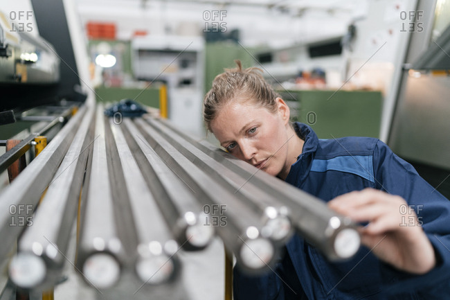 Young woman working as a skilled worker in a high tech company- checking steel rods