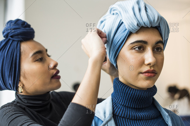 New York City, NY, USA - February 13, 2017: Woman helping model get dressed in blue outfit backstage during the Mara Hoffman fashion show