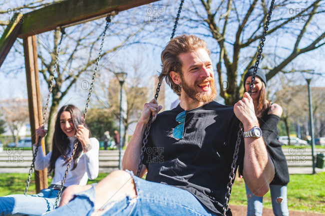Young woman and young man swinging outdoor having fun