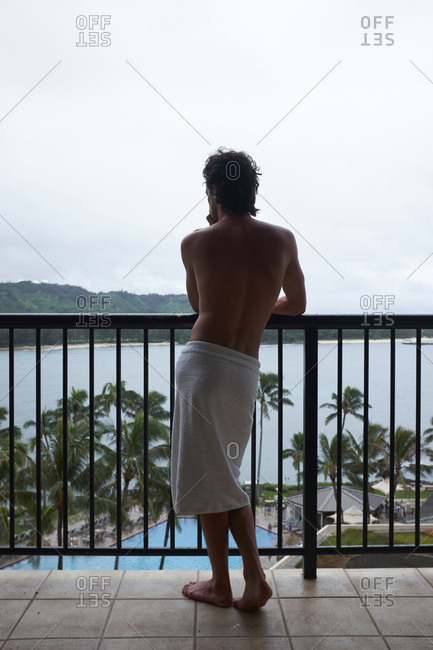 Man in towel on balcony of hotel in Hawaii