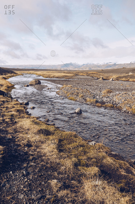 Mountain river streaming between brown grounds and view on lowland in Iceland