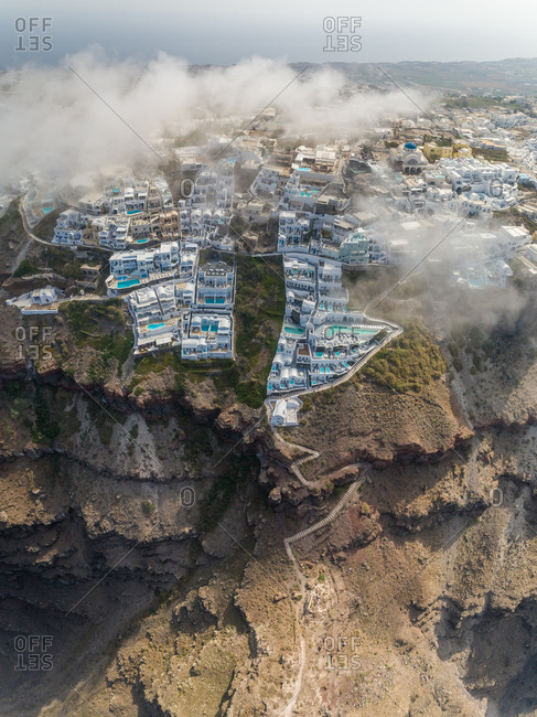 Aerial vertical view over the clouds of traditional white houses on Santorini island, Greece.