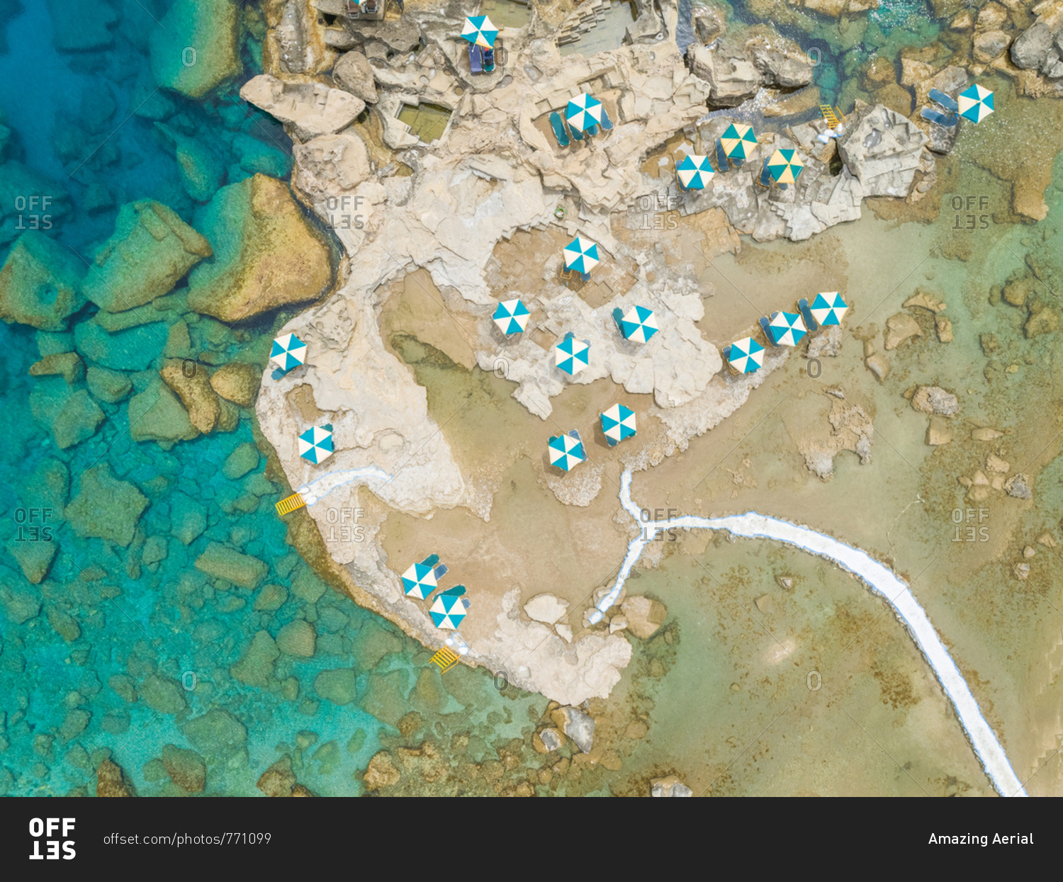 Aerial view of blue and white parasols on rocky coast, Rhodes island