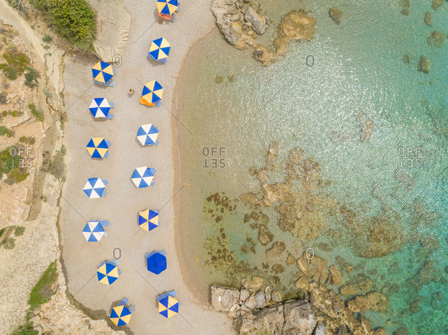 Aerial view of checkered parasols on the shore of Rhodes island, Greece.