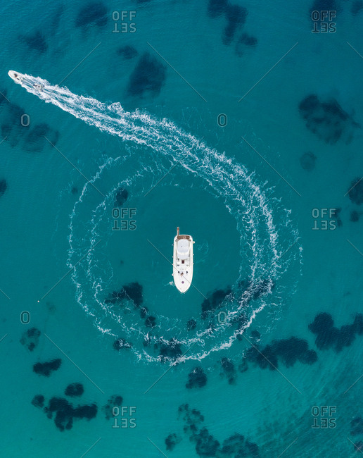 Aerial view of jet ski circling around yacht in the mediterranean sea, Mikonos island, Greece.