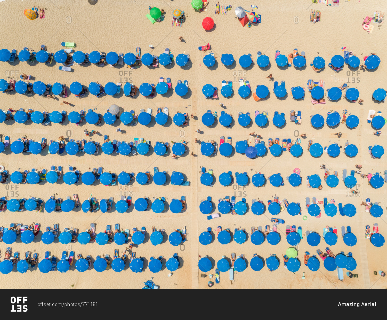 Aerial view of crowded beach with blue parasols on Lefkada, Greece.