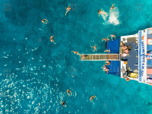 ITHAKI - GREECE, AUGUST 9 2018: Aerial view of people on ferry diving into sea, Ithaki island, Greece.