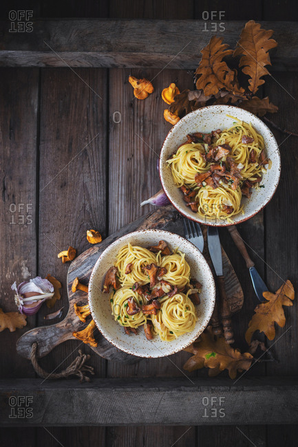 Pasta with freshly picked chanterelle mushrooms, cheese and herbs on old wooden table