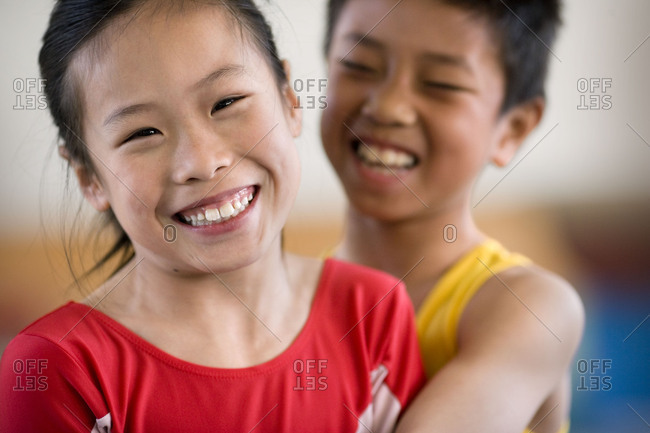 Portrait of a girl being hugged by a boy in a gym.