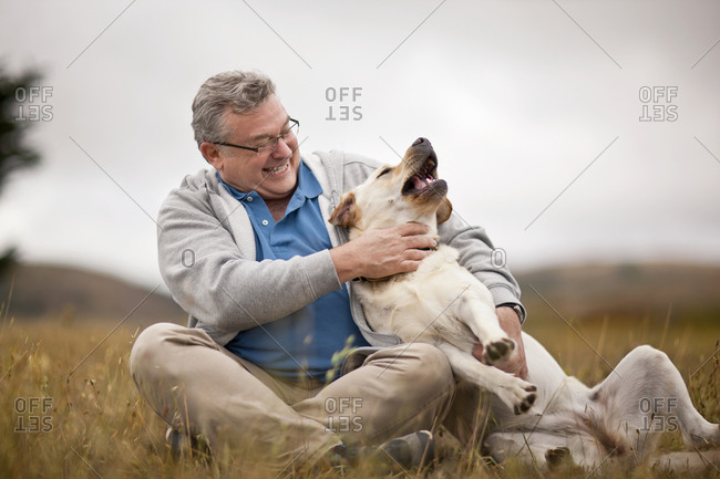 Smiling mature man playfully petting his dog.