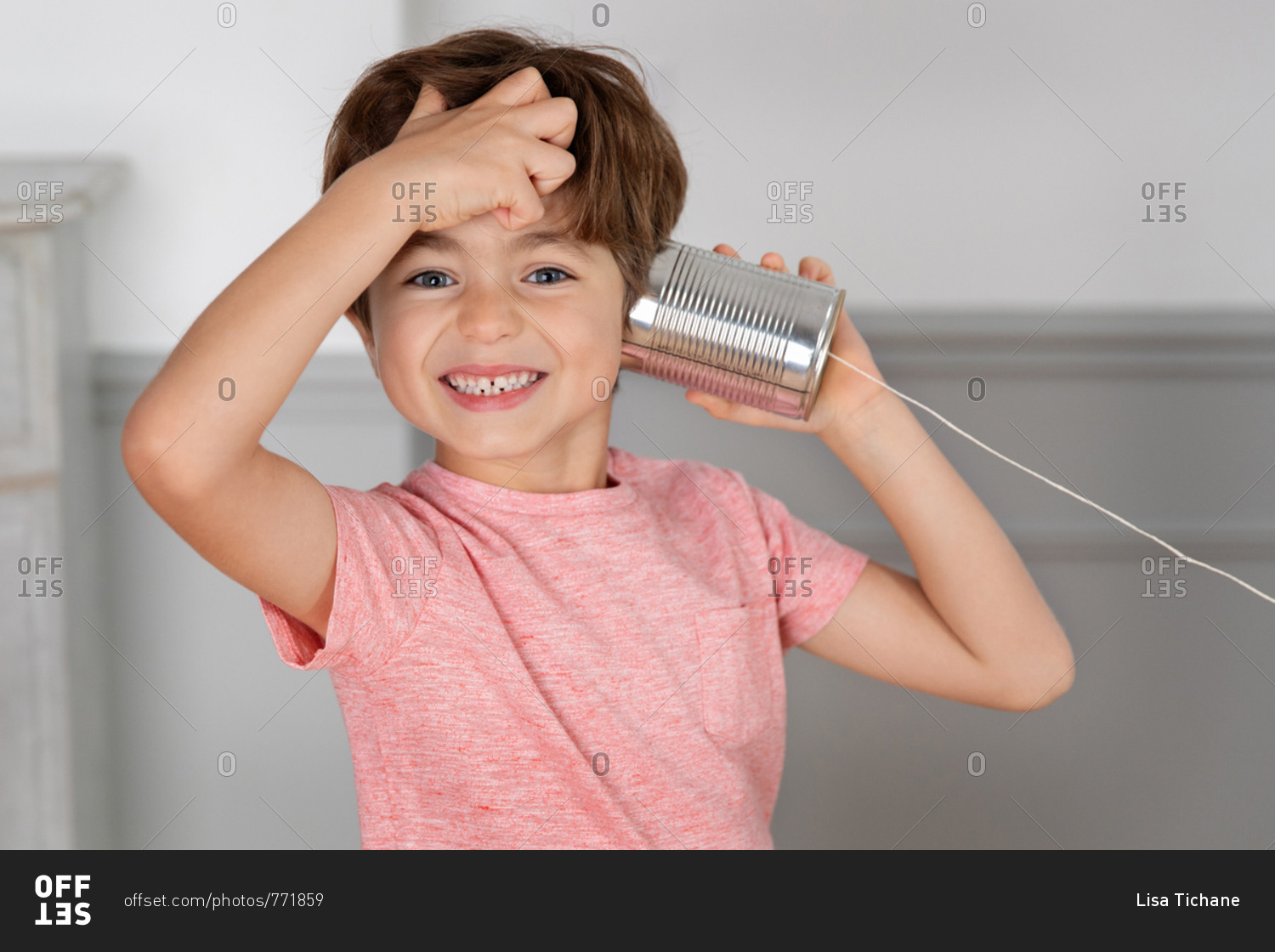 Smiling boy listening to toy telephone made with tin can and string