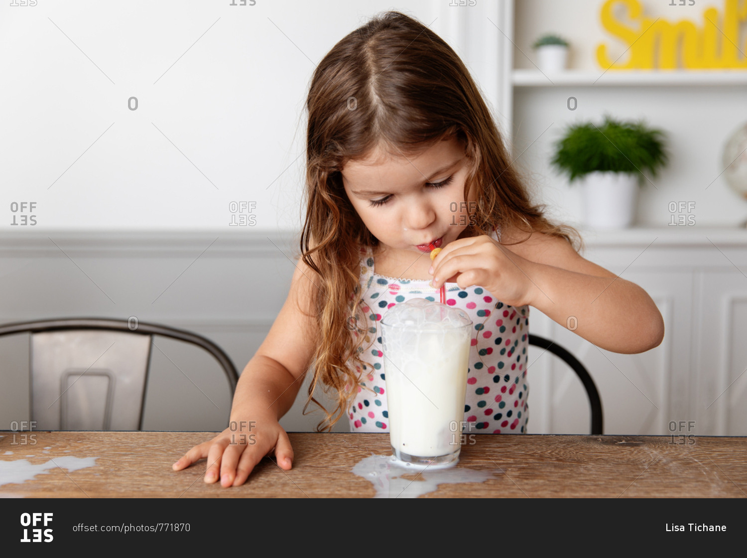 Girl blowing bubbles with straw in a glass of milk stock photo OFFSET