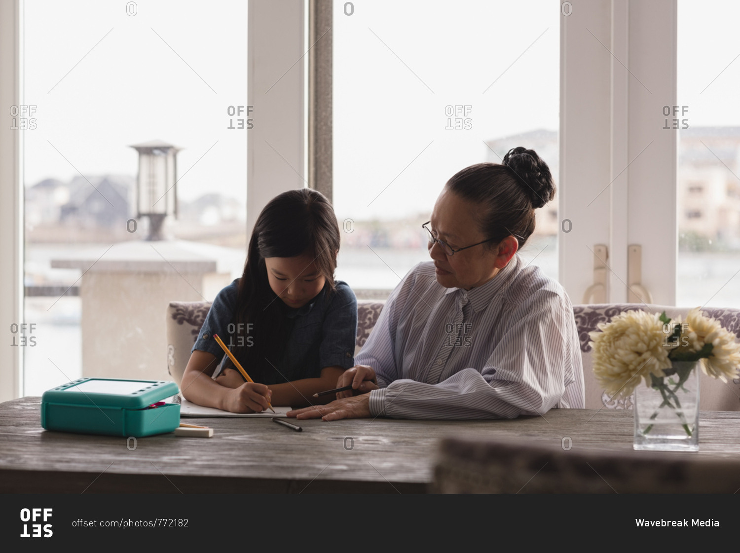 Grandmother and granddaughter drawing sketch on table at home