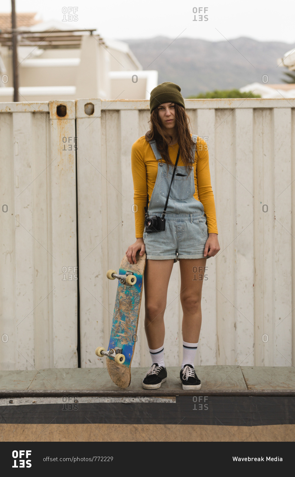 Beautiful female skateboarder standing with skateboard on skateboard ramp