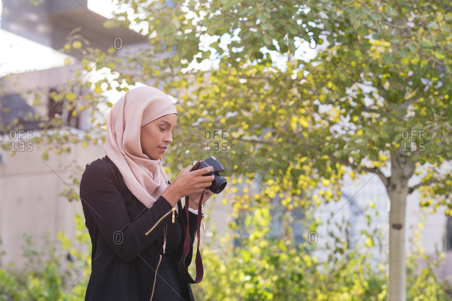 Woman clicking in camera from railing in city