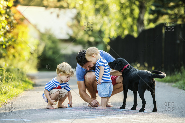 Mature man playing with his little children on the street in summer