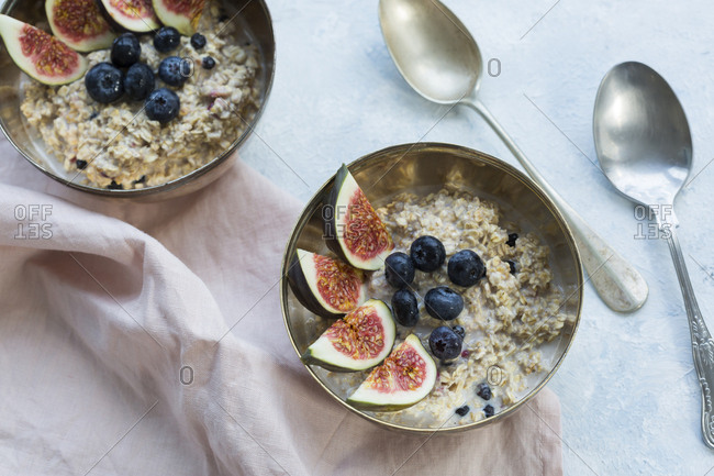Bowls of porridge with sliced figs- blueberries and dried berries