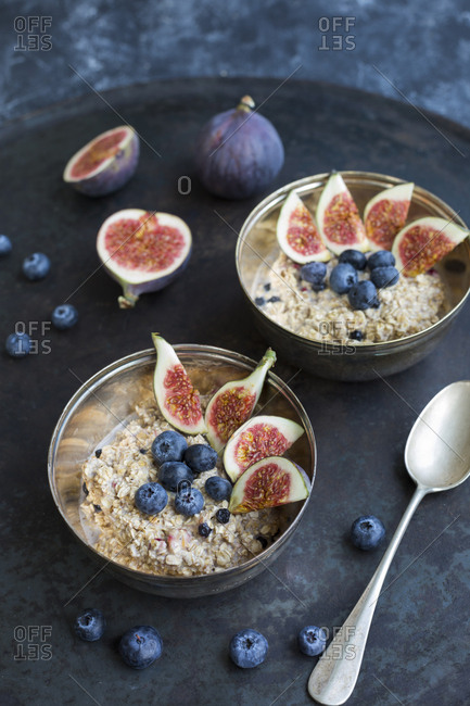 Bowls of porridge with sliced figs- blueberries and dried berries