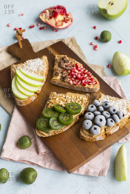 Bread slices with various toppings on wooden board