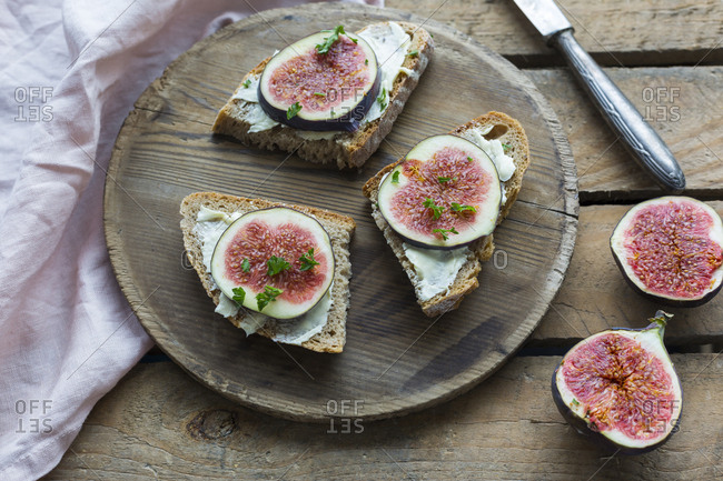 Buttered slices of bread with sliced figs on wooden plate