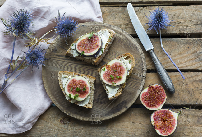 Buttered slices of bread with sliced figs on wooden plate