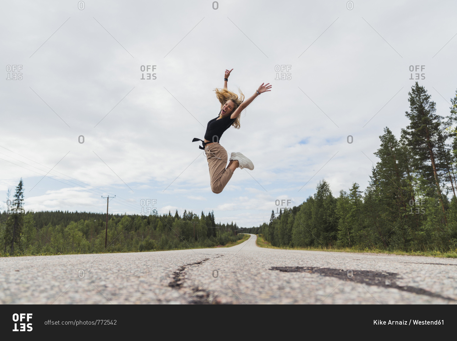 Finland- Lapland- exuberant young woman jumping in rural landscape