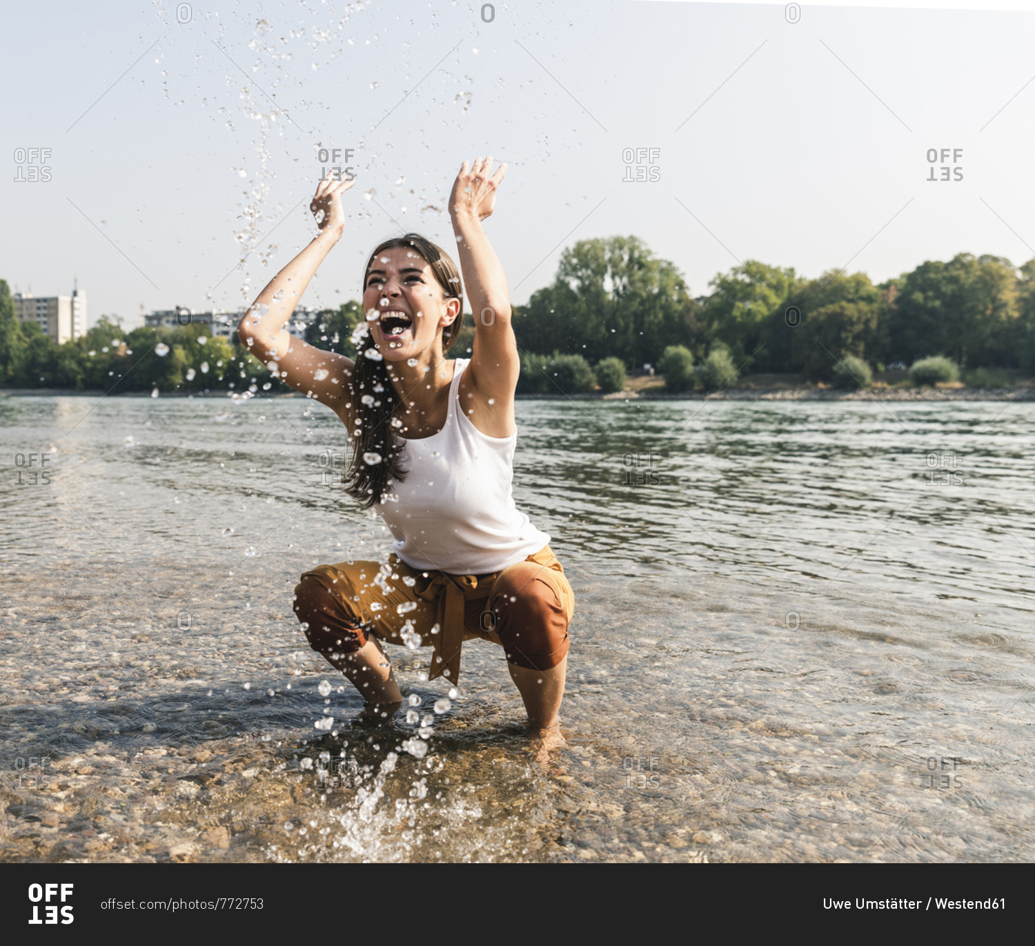 Carefree young woman refreshing in water of a river