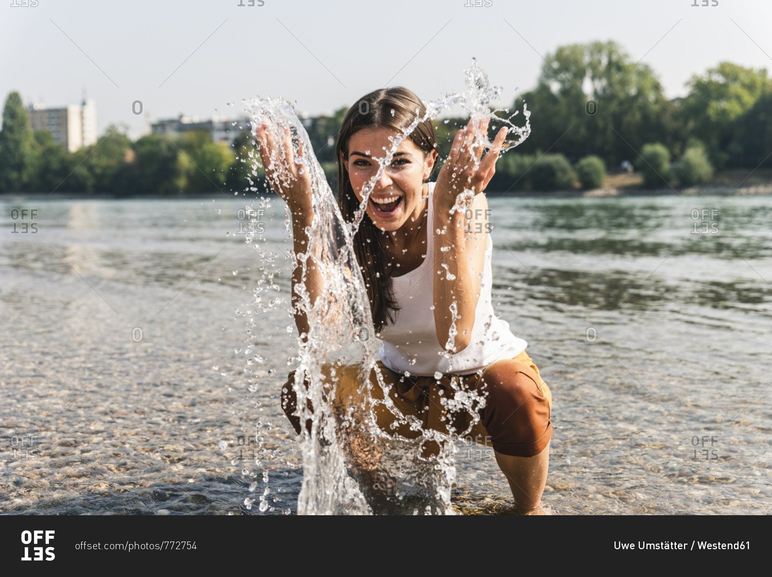 Carefree young woman refreshing in water of a river