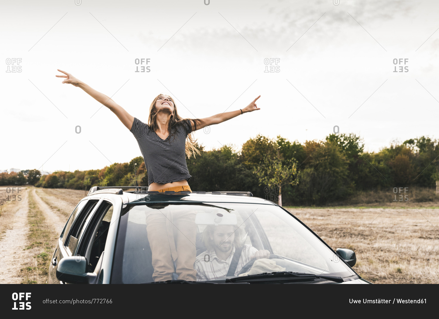 Carefree young woman looking out of sunroof of a car