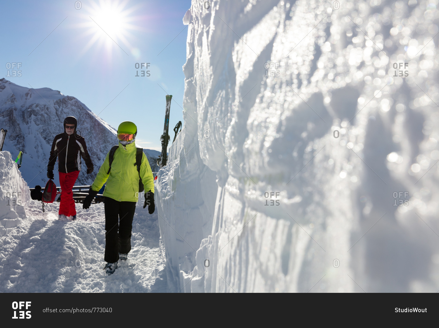 Senior couple in ski gear walking towards ski bar on sunny day