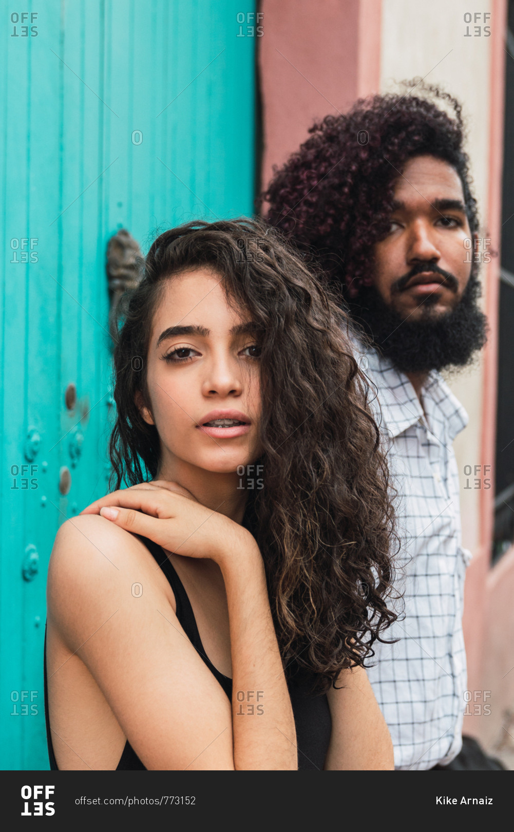 Young Hispanic man and charming woman with hand on shoulder in casual wear looking at camera near door on street in Colonial Zone in Santo Domingo city, Dominican Republic