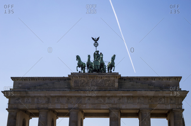 An aircraft flies far above the Brandenburg Gate in Berlin, Germany.