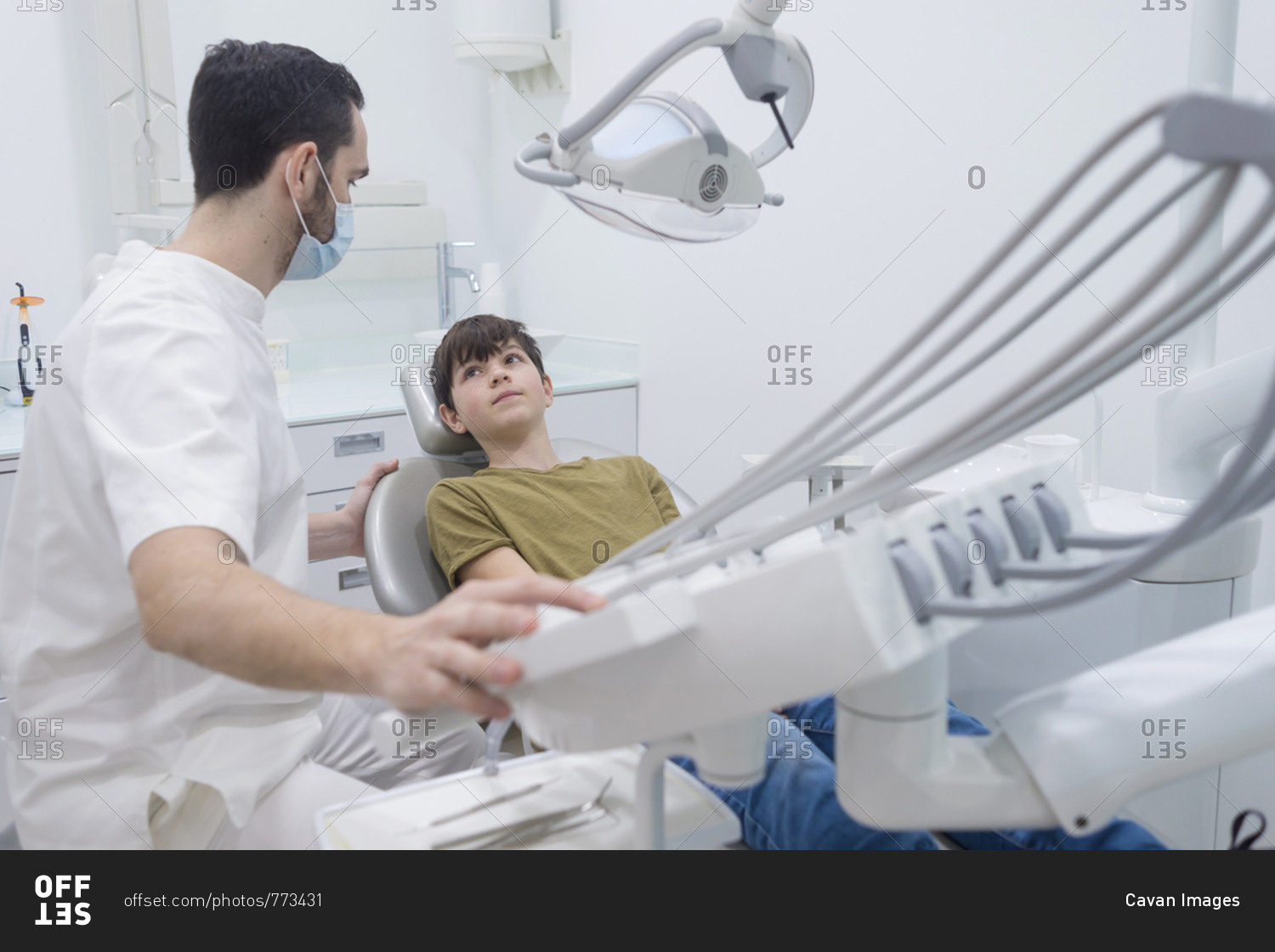 Dentist touching machinery while looking at patient in medical clinic