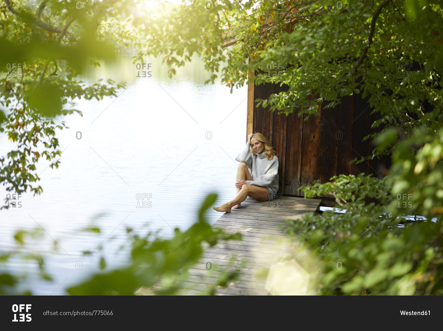 Relaxed woman sitting on wooden jetty at a remote lake