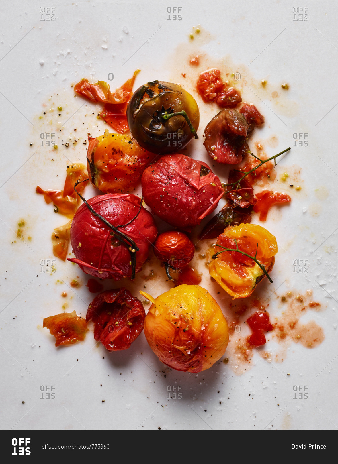 Messy red and yellow tomatoes and seasoning on white background