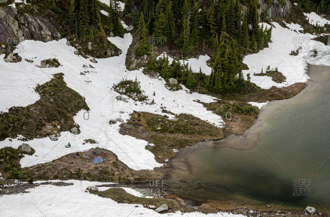 Three people set up camp at Semaphore Lake, an alpine lake and meadow area with relatively easy access from a logging road making it a popular backpacking destination, Pmeberton, British Columbia, canada